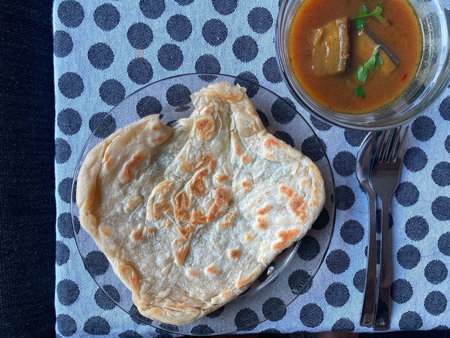 A flaky flatbread with a bowl of curry, on a polka-dot cloth.