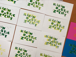 A spread of hand-printed linocut cards reading ‘Klein rustig zacht’ in green ink.