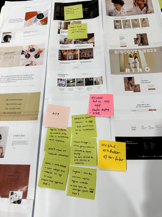 Printed website layouts on a wall, annotated with sticky notes during the visioning workshop.